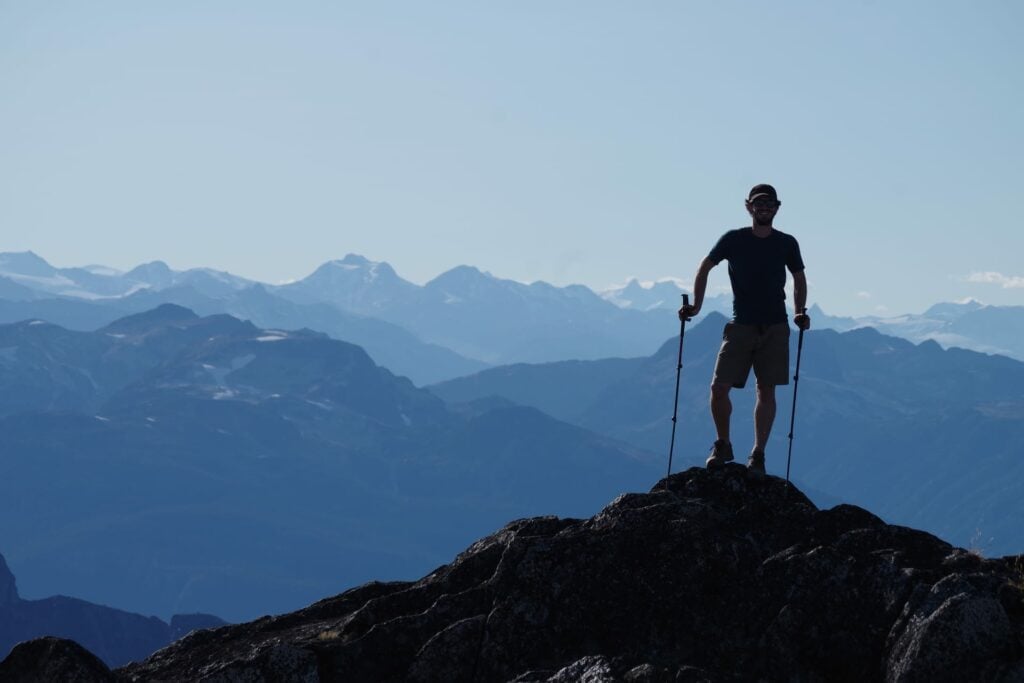 Man stand on top of mountain with layers of panorama behind.