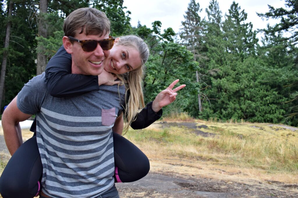 Blaize jumping on Mike's back, laughing and giving a peace symbol.