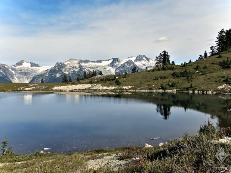 Calm reflections of distant trees and mountains at Elfin Lakes