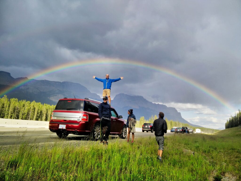 A double rainbow over the Icefields Parkway, with Seb standing on the roof of his car