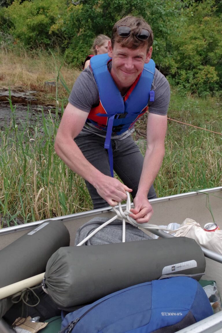 Man looking happy to have arrived at the campground, and unpacking the canoe.