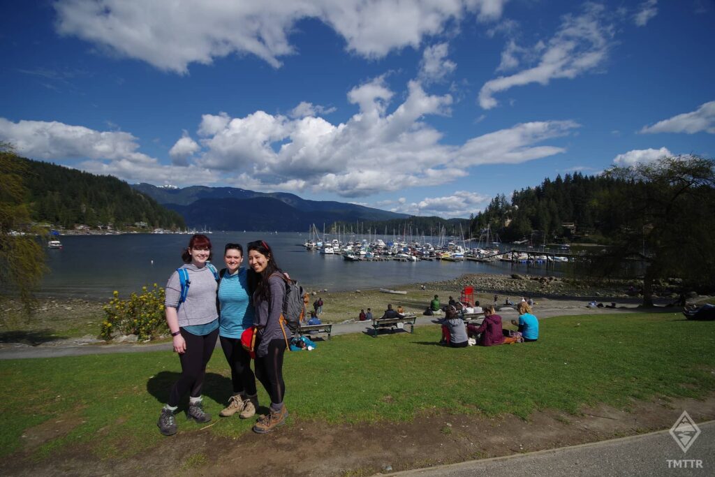 Three women standing in front of the marina at Deep Cove.
