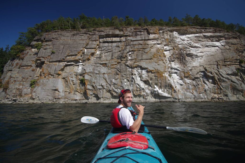 Jerome in the front of our kayak with a huge cliff in front.