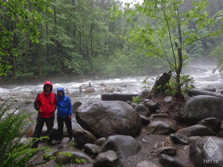 Couple standing by river, getting rained on.
